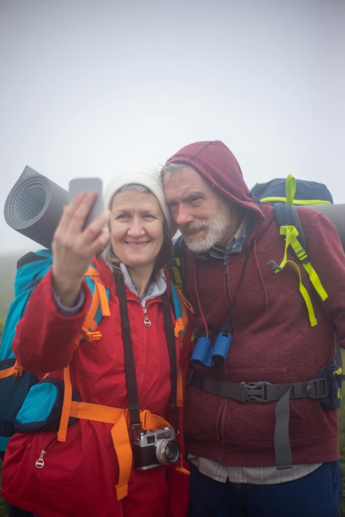 older couple with hiking and camping gear taking a selfie. The image illustrates a writing exercise in which characters tell the story of how they first met.