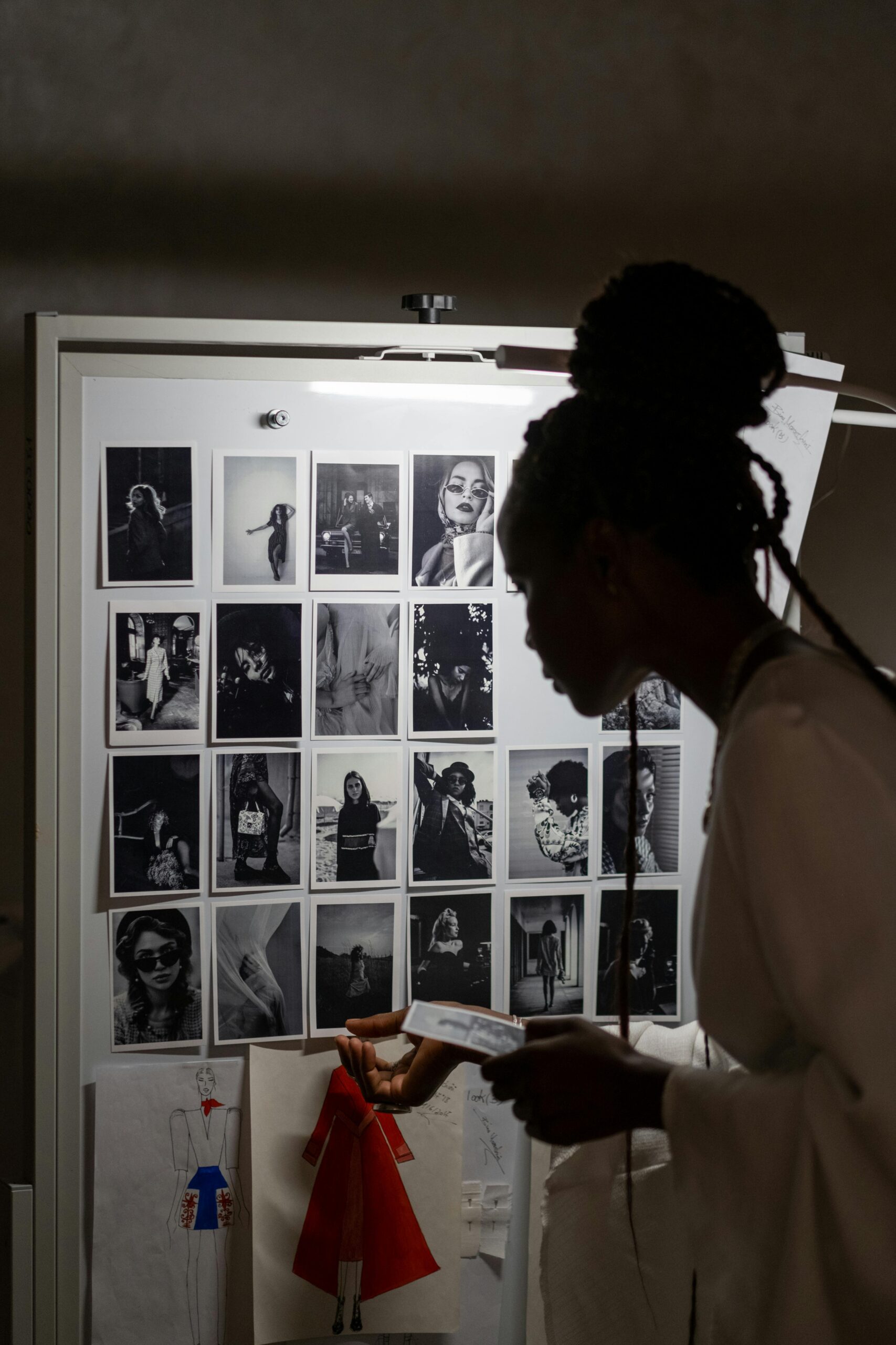 Image of a woman re-arranging black and white pictures on a wall. The image illustrates the writing exercise in which you change a few things from truth to fantasy to allow yourself to get creative with your memories